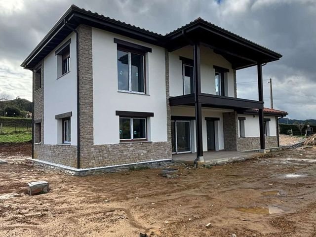 Vivienda unifamiliar de dos plantas con fachada de piedra y revoco, en fase de obra